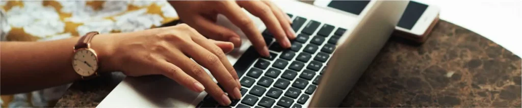 Mãos de uma pessoa navegando em um notebook, representando a leitura de conteúdos no blog da OBRAP Engenharia de Avaliações